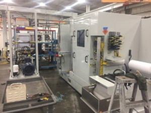 Newly painted roller machine in a shop manufacturing environment with a man in a ballcap looking down standing in the background.