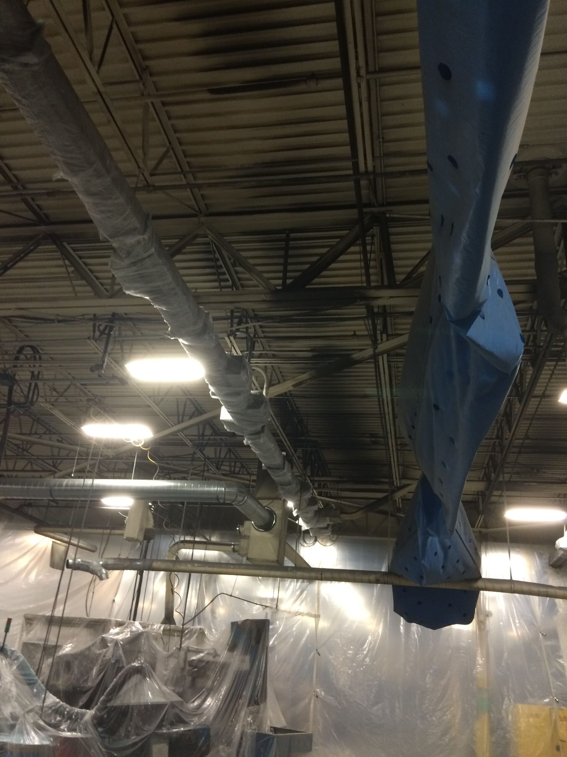 Man on aerial lift cleaning ceiling of industrial building